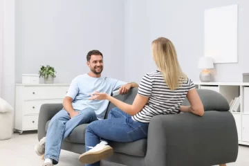 Pariskunta keskustelee terapiatilan sohvalla kuvastaen sitä, miten voi valmistautua pariterapiaan tai ohjaukseen.